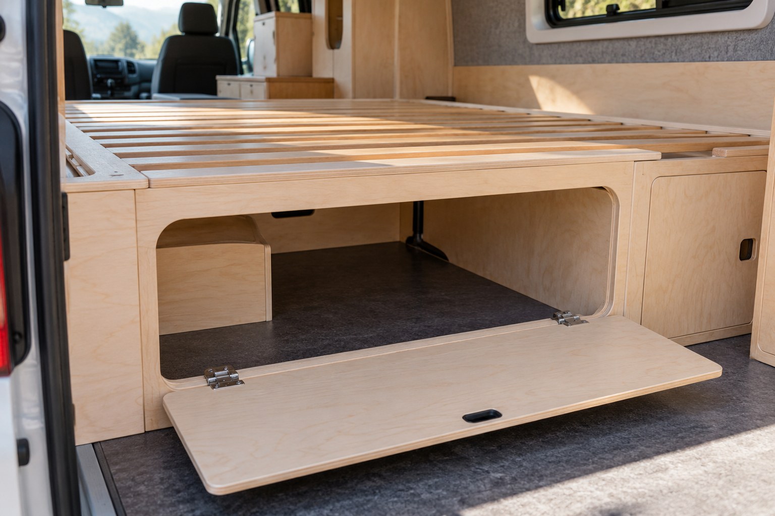 Bed base with an open storage access panel inside a van